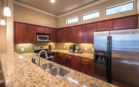 View of kitchen sink, dishwasher, fridge, oven, microwave, coffee maker, mugs and coffee grounds, sugar and half and half 