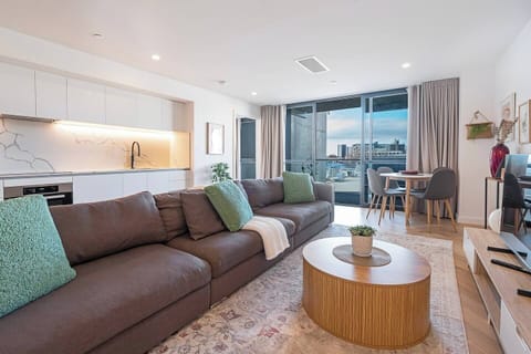 Step into the inviting living area, where cooking, dining and relaxing blend effortlessly — with a spacious sofa, sleek kitchen, and easy access to the breezy balcony.