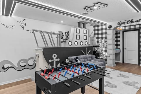 Step into a playful game room featuring a foosball table that invites friendly competition. With whimsical black-and-white decor, including charming wall art, this space creates a fun atmosphere for relaxation and entertainment.