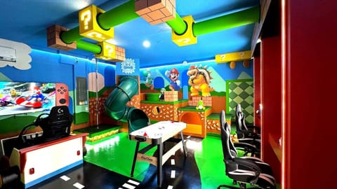 Enter a vibrant gaming paradise with lively blue walls and playful murals that spark adventure. Enjoy a sleek gaming setup, comfy chairs, and a fun slide for an unforgettable experience.