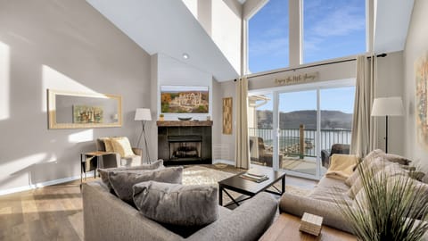 Living area with TV and Fireplace with view of the lake and access to deck.