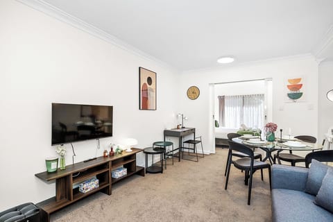 An inviting area featuring a comfortable sofa bed, stylish dining area, dedicated workspace, and a peek into the serene bedroom.