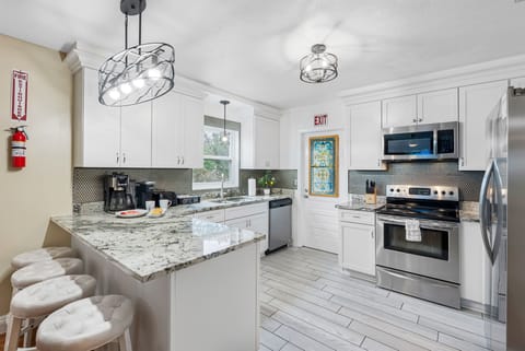 Bright, modern kitchen with white cabinetry, granite countertops, and stainless steel appliances.