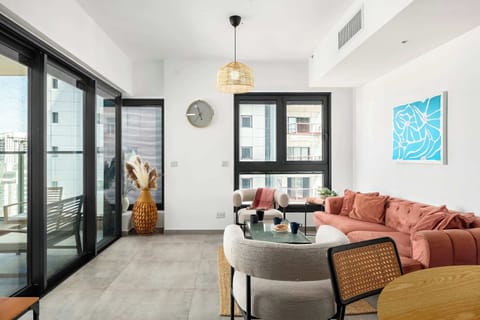 Bright open living area with soft seating, natural light, and balcony access creating relaxed modern atmosphere.