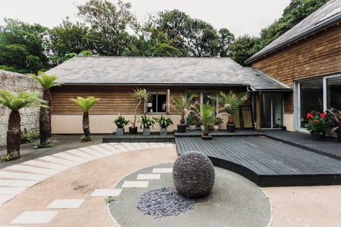 A view of of the side of the lodge, overlooking the Japanese garden, with potted palms and lush greenery.