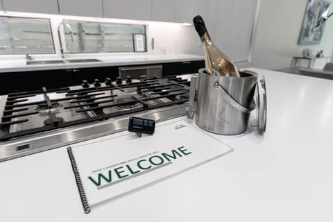 A modern kitchen island with a gas cooktop, a welcome booklet, and a champagne bottle in an ice bucket.