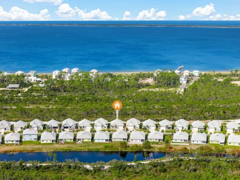 Aerial view of a coastal residential community with homes nestled between pristine blue waters and natural landscapes.
