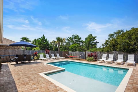 Private backyard pool with sun shelf, loungers, and patio seating