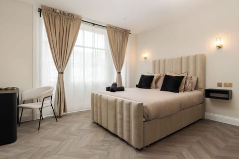 A bright, open-plan space featuring a comfortable double bed, vanity unit with mirror, wardrobe, Smart TV, and fireplace—perfect for relaxing or getting ready for a night out in the city.