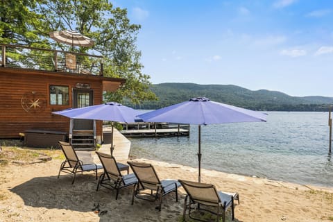 Sandy Beach area with sun loungers and a beach house with a deck

