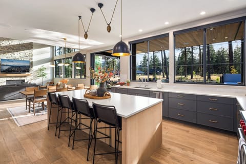 Sunlit kitchen with wide windows offering serene views of the pool and backyard.