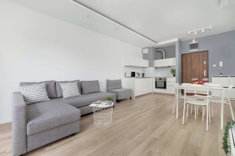 The bright living room with a comfortable sofa, wooden floor, and subtle decorations creates the perfect space for relaxing and spending time together.

