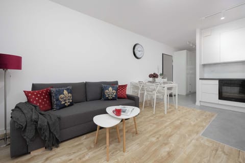A stylish living room with a fold-out sofa and red accents invites you to relax after a long day, offering a comfortable space for both work and rest.

