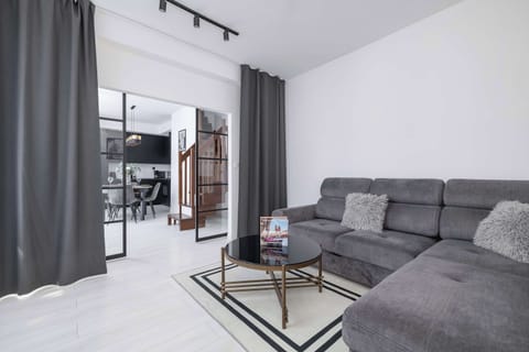 A cosy living room with a large corner sofa and a modern coffee table invites you to relax after a long day, offering a bright space with access to the balcony.