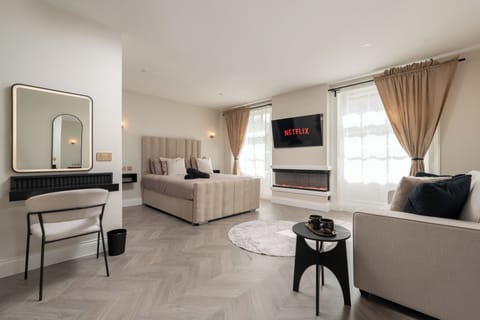 A bright, open-plan studio featuring a king bed, sofa bed with all bedding provided, Smart TV with Netflix, a wardrobe cabinet, and a dressing table that doubles as a work desk—perfect for relaxing, working, or getting ready for a night out.
