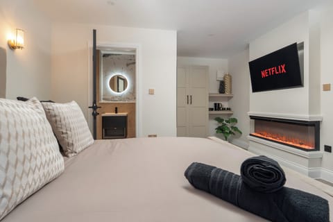 A bright, open-plan studio featuring a king bed, Smart TV with Netflix, a wardrobe, a cosy fireplace, and a dressing table that doubles as a vanity and work desk—ideal for relaxing, working, or getting ready for the day.
