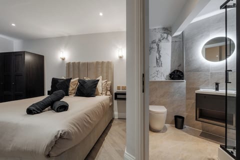 A bright, open-plan space featuring a comfortable double bed, vanity unit with mirror, wardrobe, Smart TV, and electric heater—perfect for relaxing or getting ready for a night out in the city.
