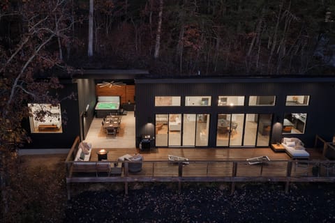 {The Iconic Glass House} Evenings flow effortlessly here—hot tub bubbling, dinner around the long table, fire-pit conversations, and a round of cornhole as the forest settles into night.