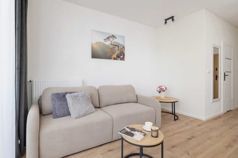 A modern living room with a light gray sofa, a small coffee table, and a neutral-colored wall.