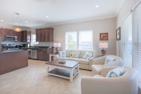 Living area in three bedroom home featuring a cozy white sofa with queen sleeper, modern kitchen, and large windows