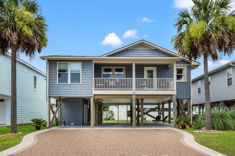 Raised beach house with a porch and palm-lined driveway at Wells Tales, a 4-bedroom Cherry Grove vacation rental
