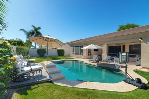 Resort-style backyard with heated pool, outdoor lounge, and sunny Arizona skies