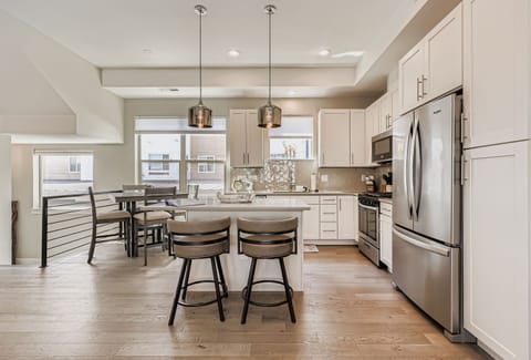 Your sleek modern kitchen features stainless steel appliances, elegant pendant lighting, and a spacious island perfect for morning coffee or evening meals.