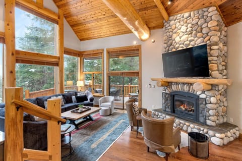 Inviting lounge w/ stone fireplace, comfy seating, & windows framing the surrounding woods