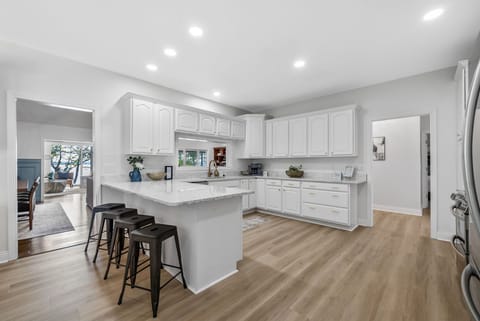 Modern kitchen with white cabinetry, ample light, and large peninsula.