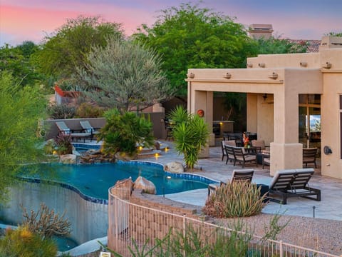 Desert oasis with a heated pool, lounge chairs, and serene sunset views.