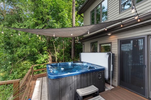 Private deck surrounded by trees, featuring a hot tub for relaxing outdoor soaks.