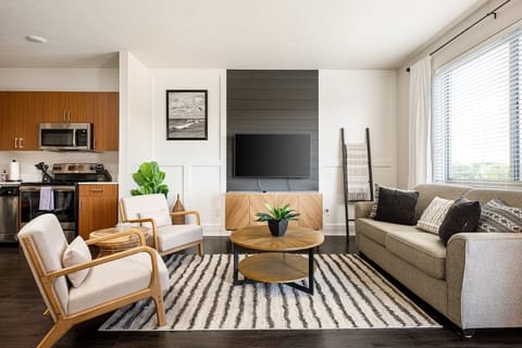 Bright, open living area w/ cozy seating, large windows & a sleek TV setup for relaxing nights in