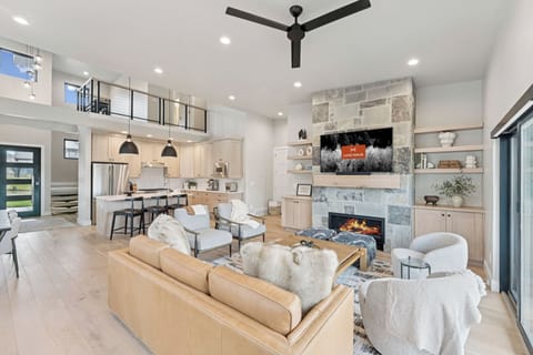 Vaulted great room with stone fireplace, sectional sofa, and open kitchen