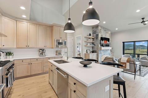 Kitchen island with bar seating, modern lighting, and open living area view.