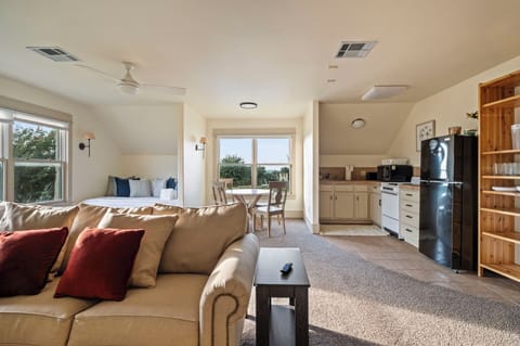 A private and spacious apartment above the garage featuring a queen daybed, a TV, two armchairs, and a three-person sofa for comfortable lounging.