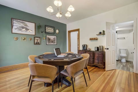 Welcome to Noble Crest! The dining area combines style and function with a modern chandelier, bold accent wall, and a versatile table that transforms into a poker table for game nights.