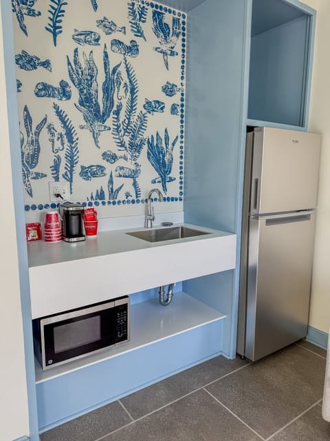 Stylish kitchenette with artistic blue detailing, stainless refrigerator, and built-in microwave for added comfort.