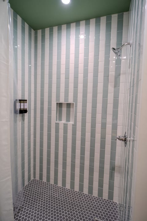 Tiled walk-in shower with rainfall head, in-shower niche, and eco-friendly body products