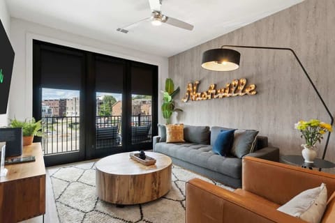 Inviting living area featuring a Nashville sign, a large window, and balcony access.