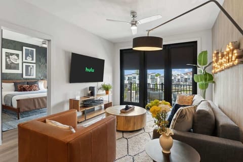 Spacious and stylish living room with a large TV and balcony access.