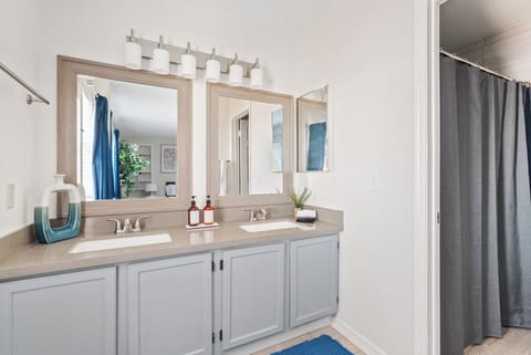 Primary Bathroom:  The ensuite bathroom features dual sinks, a spacious shower, and hotel-quality amenities including shampoo, conditioner, shower gel, lotion, and thoughtful extras like a hairdryer and toothbrushes conveniently stored under the sink