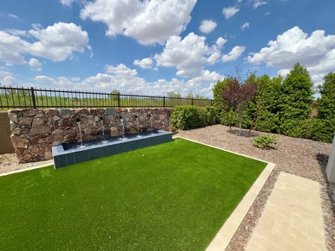 Backyard grass and fountain area with desert views behind home