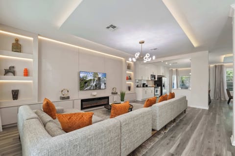 Elegant living room and open kitchen with striking orange accents.