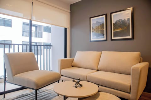 Cozy seating area with beige armchairs and framed wall art near large windows.