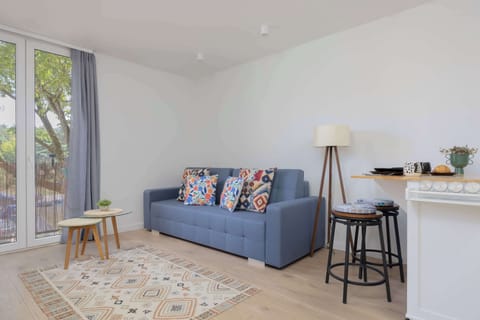 A bright living room with a large window and balcony access invites you to relax on a comfortable sofa surrounded by natural light.