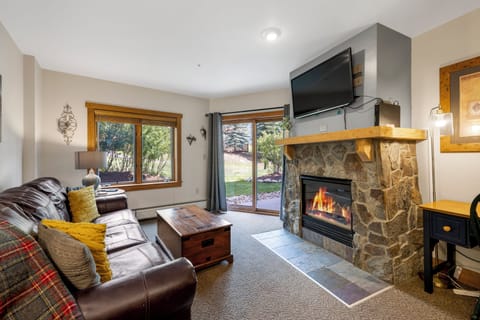 Living room with cozy fireplace and TV. The Living Room leads right out to your private patio where youve got views of the ski hill right there!