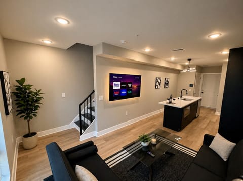 The living room is tastefully furnished with two futon sofa beds, a spacious 50-inch television featuring a wide selection of Ruku channels, and an abundance of invigorating natural light that gracefully floods the room through the large windows.