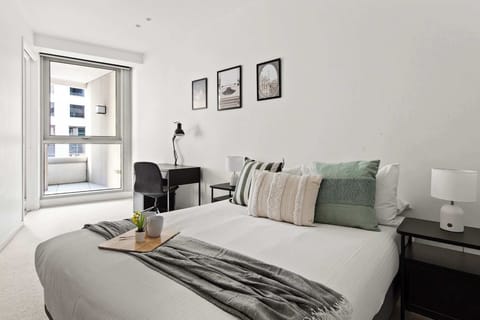 A bedroom with a queen sized bed & plush pillows with a study area.