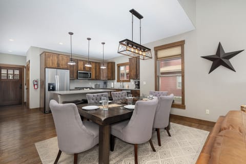 Gather around your elegant dining table in this open-concept space where warm wood tones and modern fixtures create the perfect atmosphere for memorable meals.