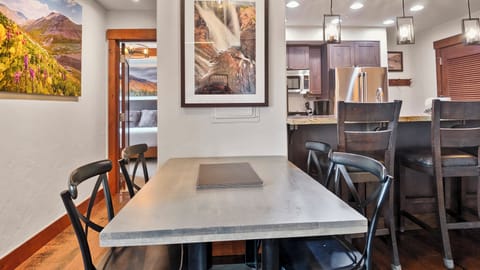 Four-seat dining table by kitchen and mountain artwork.